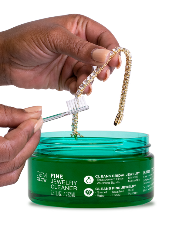 Hands cleaning a tennis bracelet with a jar of Fine Jewelry Cleaner