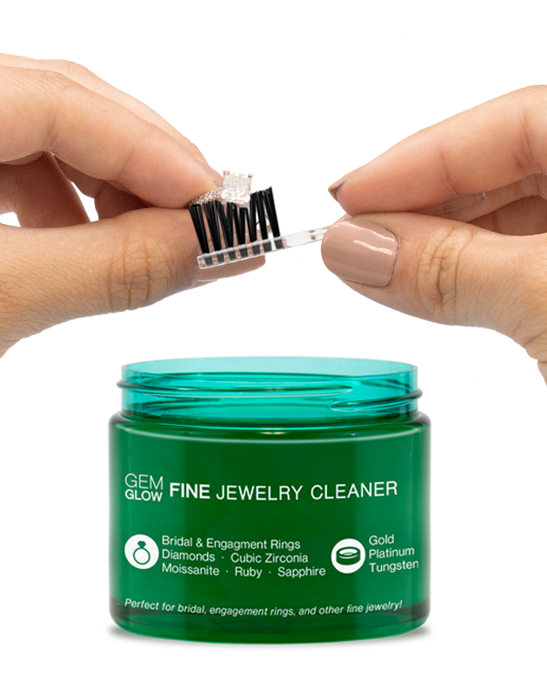 Hands cleaning a diamond ring with a jar of Fine Jewelry Cleaner