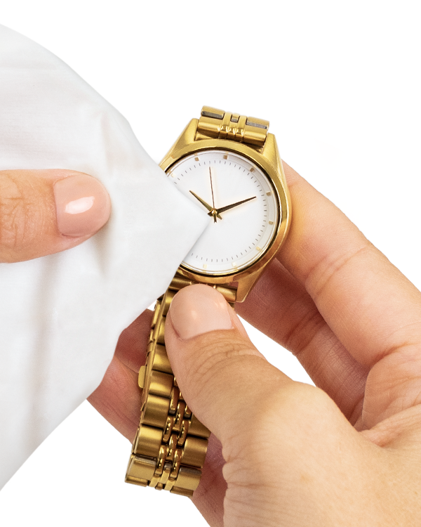 Hands cleaning a gold watch with a Jewelry & Watch Cleansing Wipe towelette